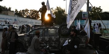 A Taliban ranger patrols through a bustling Kabul square, accompanied by armed militants, highlighting the group's presence in urban settings. (Photo Credit: Wakil KOHSAR / AFP)