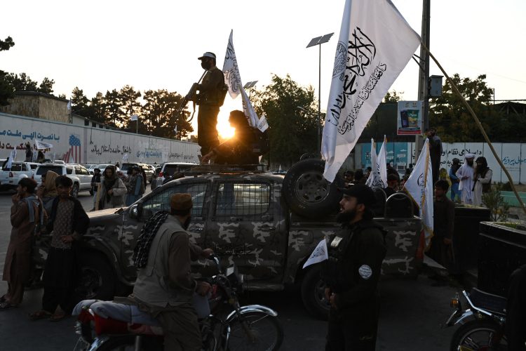 Taliban militants ride in a convoy through Kabul, as evening falls over the city. The Taliban's ties with terrorist groups, like al-Qaeda, persist. (Photo Credit: Wakil KOHSAR / AFP)
