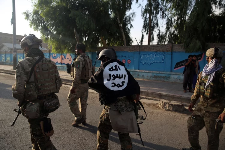 Armed Taliban fighters in uniform, with an ISIS flag displayed on the back of one of them, conduct an operation in Afghanistan. (Photo Credit: AP)