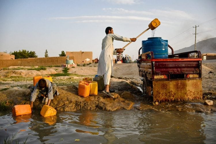 A young Afghan child and a man gather water from a spring in a Kabul village, highlighting the struggle for clean water access amid the city’s deepening water crisis. (Photo Credit: Atif Aryan / AFP)