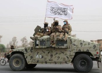 Taliban fighters atop a U.S. Humvee in Kabul, marking their takeover as the group’s flag waves from the vehicle. (Photo Credit: AP)