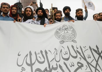 Taliban fighters hold a flag for the Islamic Emirate of Afghanistan in August 2022. (Photo Credit: Ali Khara/Reuters)