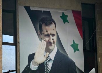 A defaced portrait of Syrian President Bashar al-Assad in a public setting. (Photo Credit: OZAN KOSE / AFP)