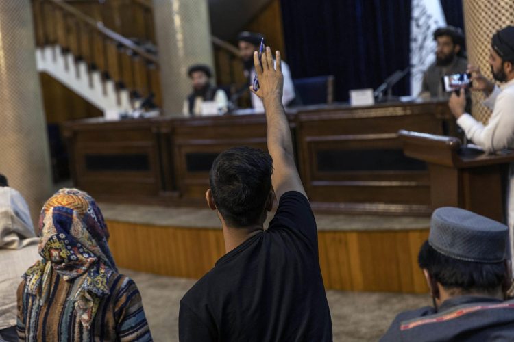 A journalist raises their hand to ask a question during a press conference with Taliban officials in Kabul, Afghanistan. (Photo Credit: Victor J. Blue/The New York Times)