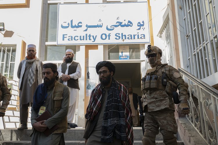 Taliban officials and armed personnel exit the Faculty of Sharia building at a university in Afghanistan, reflecting the group's growing influence over academic institutions. (Photo Credit: Wakil KOHSAR / AFP)