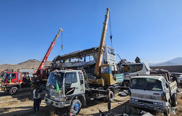 Cranes work to remove a damaged passenger bus involved in a traffic accident in Afghanistan, highlighting the ongoing challenges of road safety in the region. (Photo Credit: MOHAMMAD FAISAL NAWEED / AFP)
