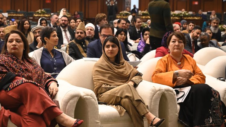 Malala Yousafzai, flanked by two women, at the OIC conference in Islamabad, with the audience in the background. (Photo Credit: AFP)