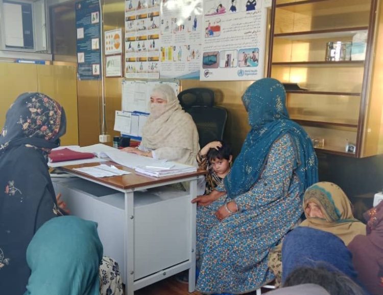 An Afghan woman, accompanied by children, receives medical consultation at a UNFPA-supported border health clinic following deportation from Pakistan. (Photo Credit: UNFPA/X)