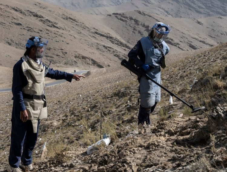 Demining personnel work cautiously on a mine-contaminated hillside in Afghanistan, as part of ongoing efforts to clear explosive remnants of war. (Photo Credit: OCHA)
