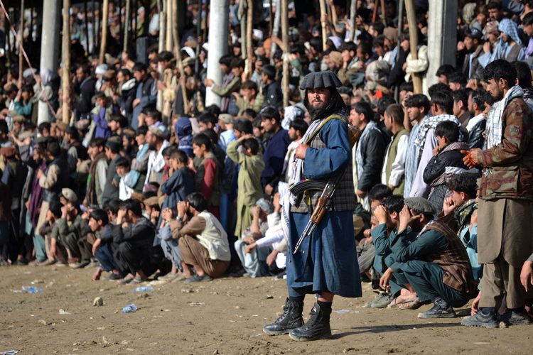 A Taliban fighter stands guard as spectators gather for a local sporting event in Afghanistan. (Photo Credit: AFP)