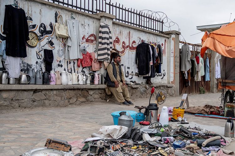 A street vendor sits beside his goods along a roadside in Kabul, amid Taliban restrictions limiting their operations after 4 p.m., as economic challenges persist. (Photo Credit: AFP)
