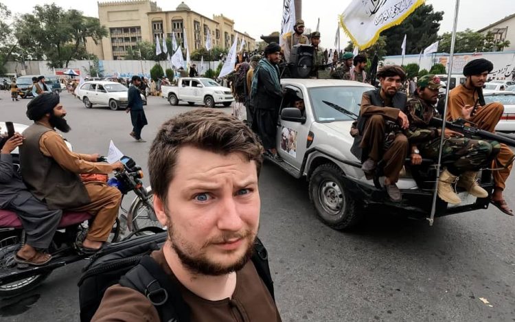 A foreign tourist takes a selfie amid Taliban fighters in Afghanistan, highlighting the stark contrast between tourism and local realities. (Photo Credit: Callum Darragh/Telegraph)