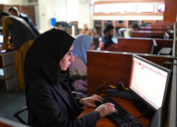 A female student works intently at a computer in a university lab, determined to pursue education amid increasing restrictions. (Photo Credit: AFP)