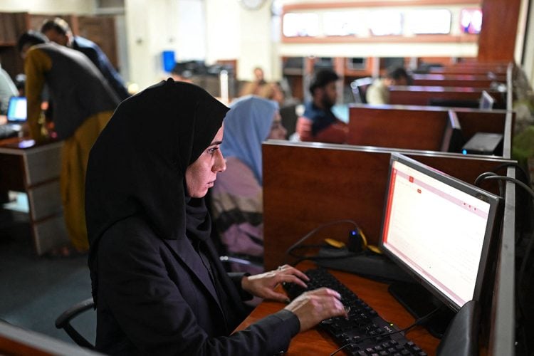 A female student works intently at a computer in a university lab, determined to pursue education amid increasing restrictions. (Photo Credit: AFP)