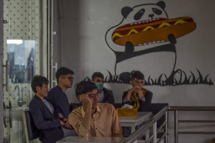 Young Afghan men sit idly at a café in Kabul, reflecting the despair and isolation many feel amid growing unemployment and lack of prospects. (Photo Credit: AFP)