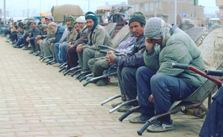 Job seekers sit idle along a street in Afghanistan amid soaring unemployment and economic collapse under Taliban rule.