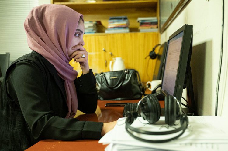 A female professor works at her desk, surrounded by books and documents, amid challenges faced by academics in Afghanistan. (Photo Credit: AFP)