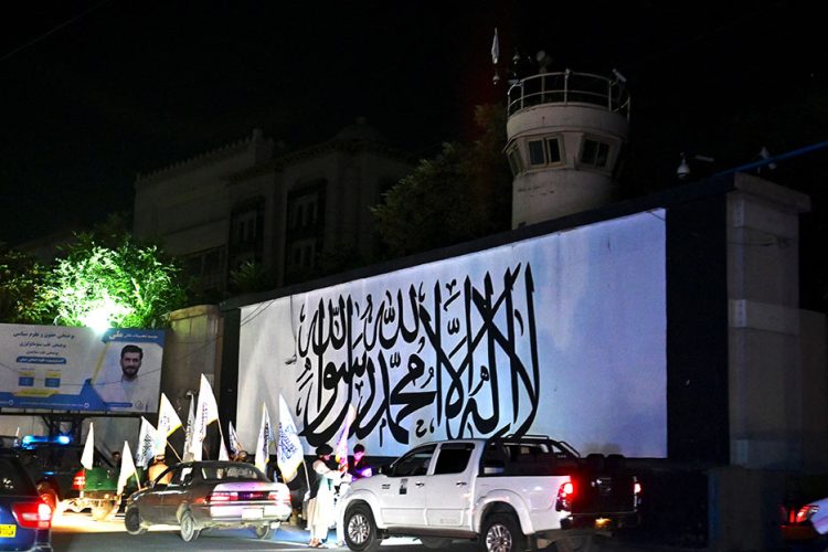 Taliban supporters celebrate the first anniversary of the U.S. withdrawal from Afghanistan in front of the former U.S. embassy in Kabul, which now bears the Taliban flag. (Photo Credit: AFP)