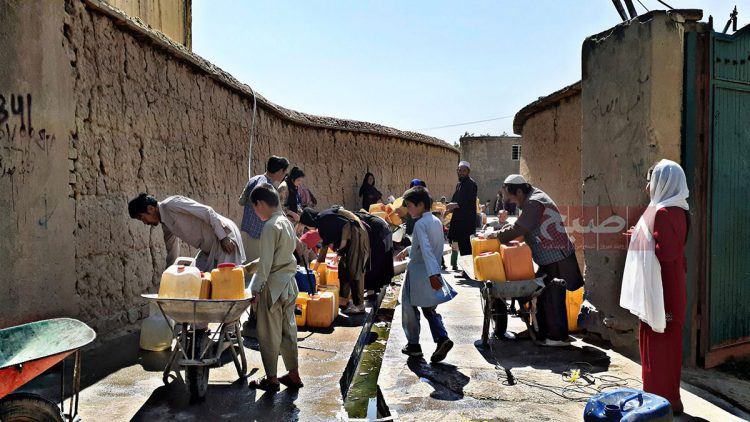 Residents of an Afghan informal settlement collect water in jugs, highlighting the lack of access to clean drinking water amid environmental challenges. (Photo Credit: 8am.media)