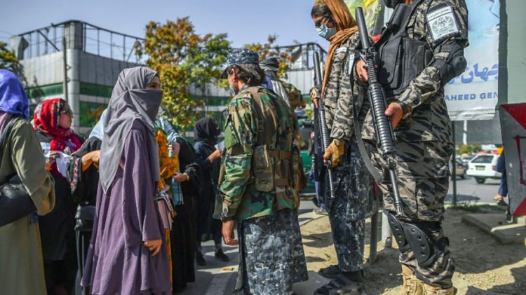 Armed Taliban members interact with women in Afghanistan, reflecting ongoing social restrictions. (Photo Credit: AFP)