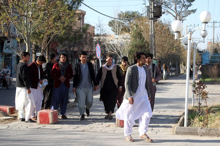 A group of men walks through a bustling street in Afghanistan, showcasing everyday life in the region. (Photo Credit: AFP)