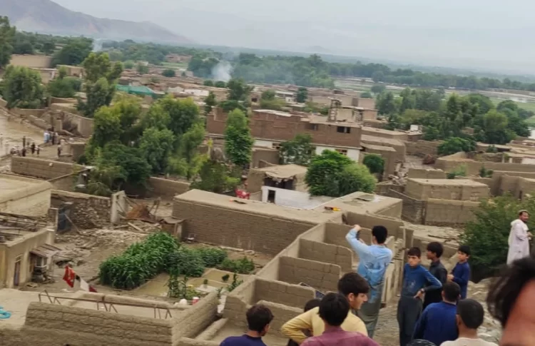 Residents observe the aftermath of flooding in a village in eastern Afghanistan, with damaged homes and gathered crowds amidst the debris. (Photo Credit: @nmic8)