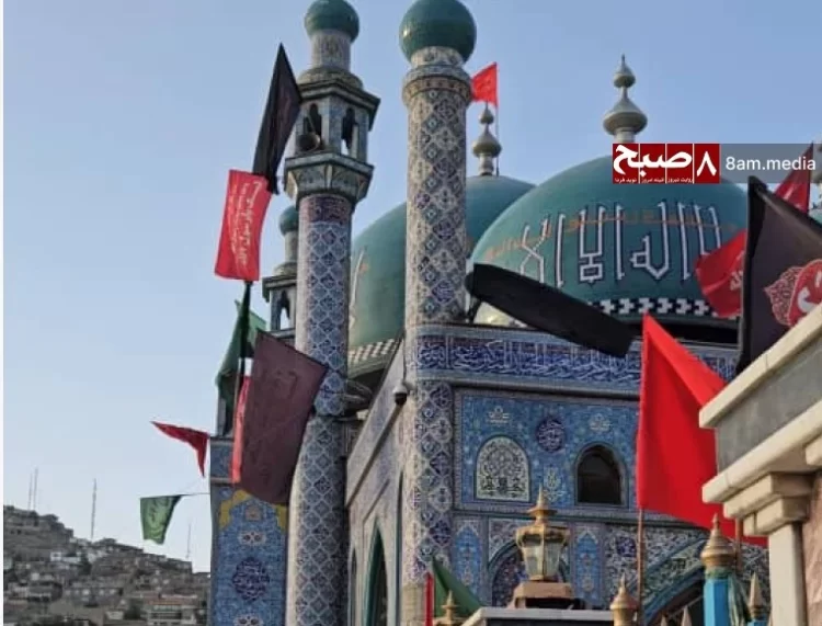 A Shiite mourner at Kabul's Kart-e Sakhi Shrine raises a religious flag during restricted Muharram ceremonies under Taliban oversight, symbolizing resilience amid suppressed religious freedoms. (Photo Credit: Hasht-e Subh Daily)
