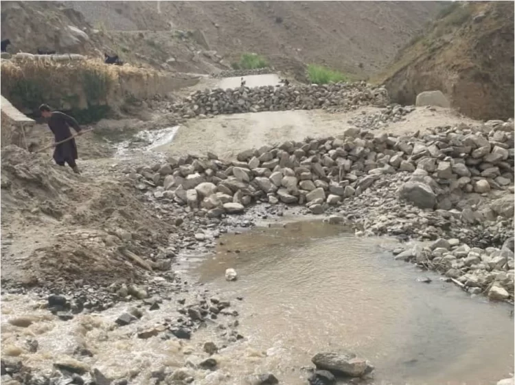 A resident works to clear a muddy stream surrounded by rocks in a rural area, as efforts continue to manage water flow in the region. (Photo Credit: Social Media)