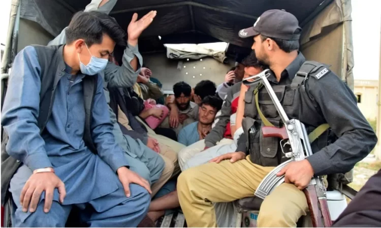 A Pakistani police officer oversees a group of Afghan refugees being transported, amid rising tensions over forced deportations. (Photo Credit: Guardian)