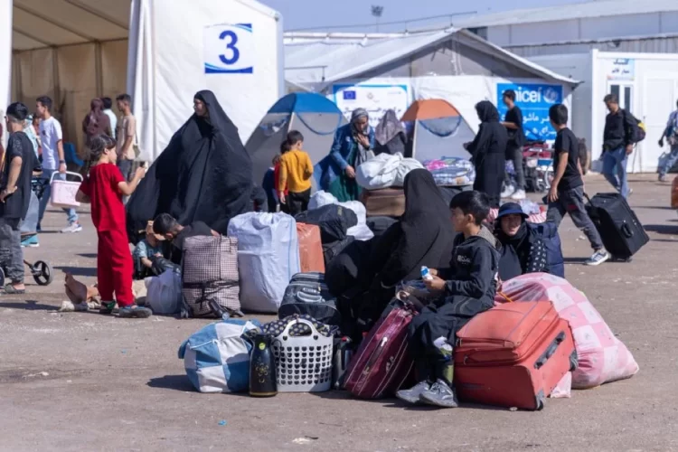 Displaced families gather with their belongings at a refugee camp, supported by UN Women and UNICEF. (Photo Credit: UN Women)