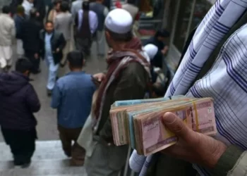 A street money changer in Kabul holds bundles of Afghan banknotes as economic uncertainty grips the country. (Photo Credit: AFP)