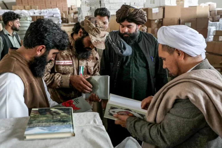 Taliban members examine books in a warehouse, part of their ongoing effort to censor literature deemed contrary to their ideology. (Photo Credit: Mohsen KARIMI/AFP)