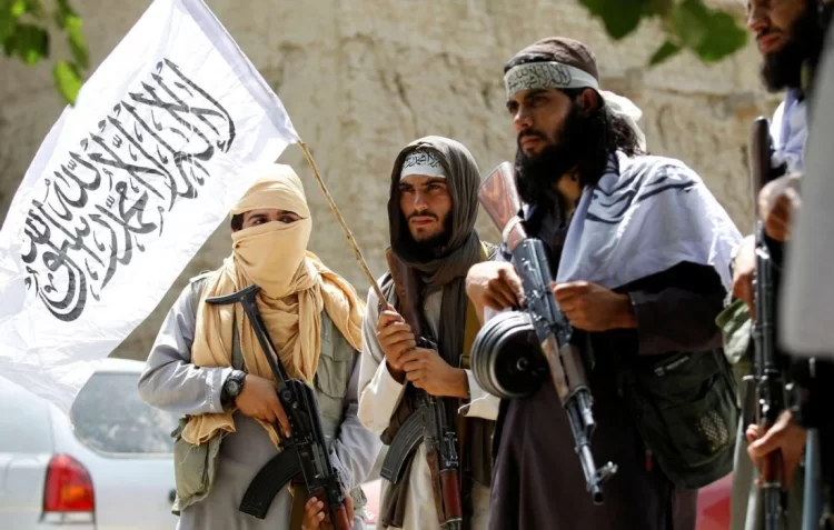 Taliban fighters stand guard with their flag in a tense display of control. (Photo Credit: iras.ir)