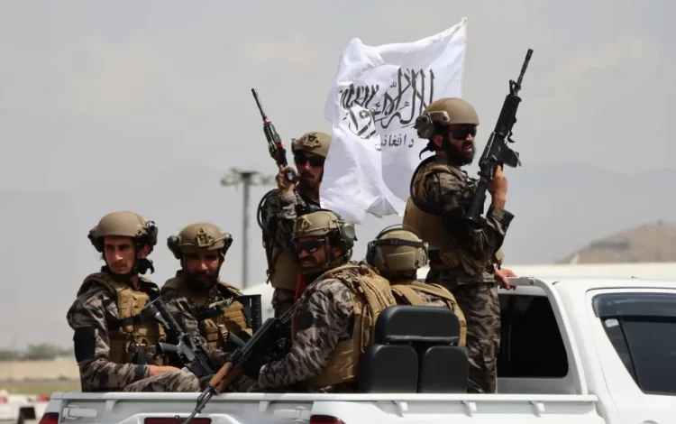 Armed Taliban fighters patrol with their flag in Afghanistan, showcasing their military presence amid reports of intelligence-led tax enforcement. (Photo Credit: Cyprus)