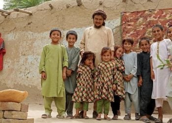 Children and a local man smile outside a traditional home in Afghanistan, a community benefiting from a UNDP project funded by South Korea to improve livelihoods and rebuild infrastructure. (Photo Credit: UNDP)