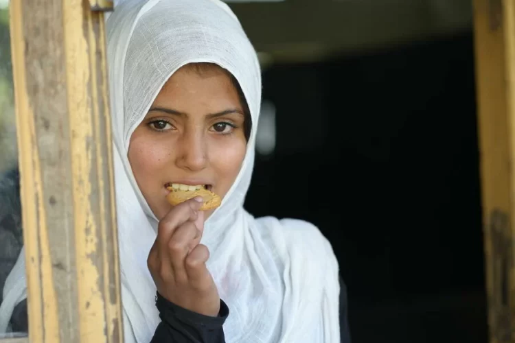 A student enjoys a fortified biscuit provided by the World Food Programme in Afghanistan. (Photo Credit: WFP)