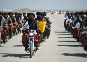Taliban fighters ride motorcycles during a military parade at Bagram Air Base, holding flags and displaying captured equipment. (Photo Credit: Ahmad SAHEL ARMAN / AFP)