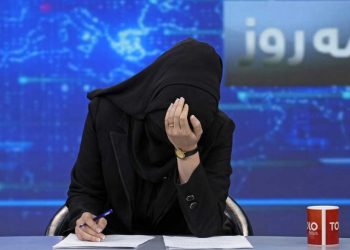 A female journalist covers her face while working at a news desk in Afghanistan, highlighting the severe restrictions and challenges faced by women in media under Taliban rule. (Photo Credit: Social Media)