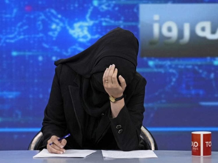 A female journalist covers her face while working at a news desk in Afghanistan, highlighting the severe restrictions and challenges faced by women in media under Taliban rule. (Photo Credit: Social Media)