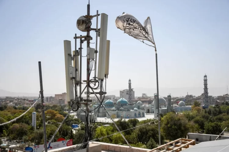 A cell tower with a Taliban flag overlooks mosques in Afghanistan, where a nationwide internet shutdown has cut off women's education and crippled essential services. (Photo Credit: Getty Images)