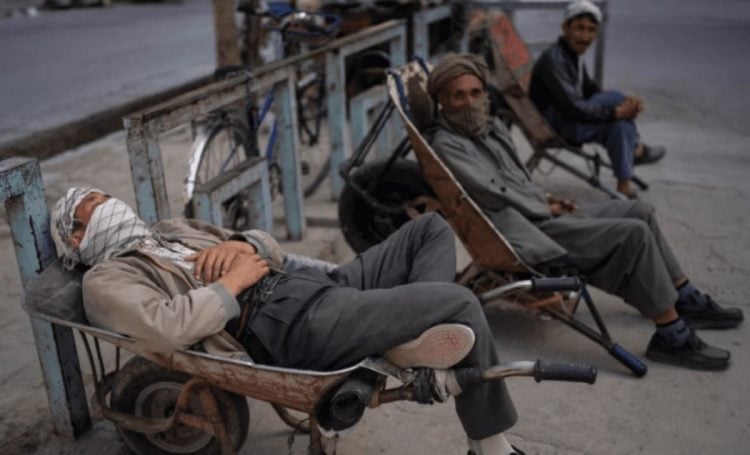 Unemployed Afghan men rest on a street in Afghanistan as economic hardship forces many to seek work through informal street-side activities. (Photo Credit: Memar Press)