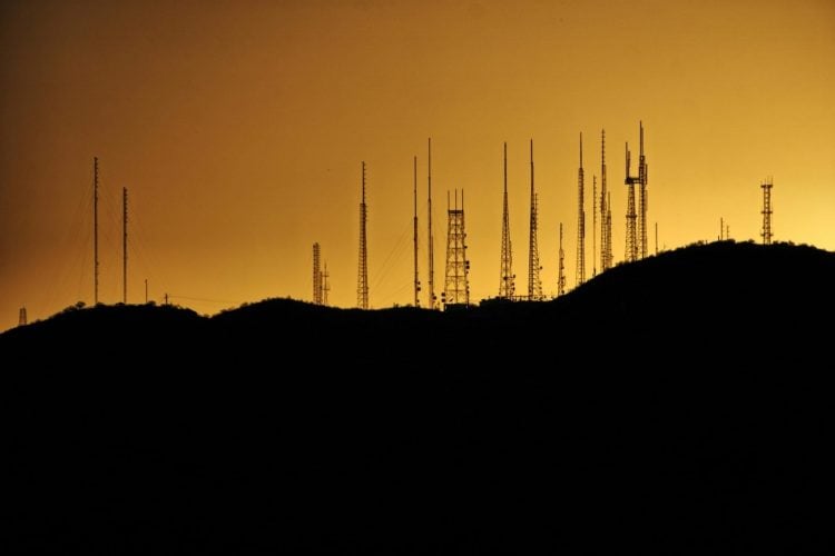 Communication towers silhouetted against a golden sunset sky, representing the telecommunications infrastructure that connects communities across Afghanistan. (Photo Credit: Pexels)