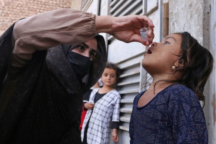 A health worker administers oral polio vaccine drops to a young girl during a vaccination campaign in Afghanistan, as part of efforts to eradicate the disease from the country. (Photo Credit: Mohsen KARIMI / AFP)