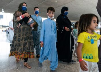 Afghan families, including children and infants, wait at an airport while processing asylum applications to Russia. Many Afghans have fled their country following the Taliban's return to power, seeking safety and better opportunities abroad. (Photo Credit: Joshua Roberts / Getty Images via AFP)