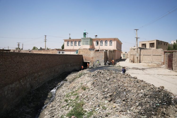 Workers address waste management challenges in an Afghan informal settlement, highlighting the critical need for proper sanitation infrastructure to protect public health. (Photo Credit: @UNHabitatAf)