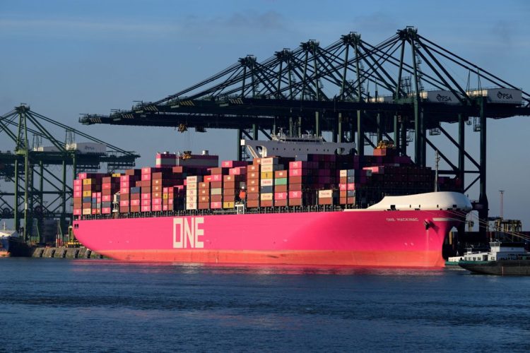 A large container ship loaded with colorful shipping containers docked at a port, representing international trade and export activities. (Photo Credit: NICOLAS TUCAT / AFP)