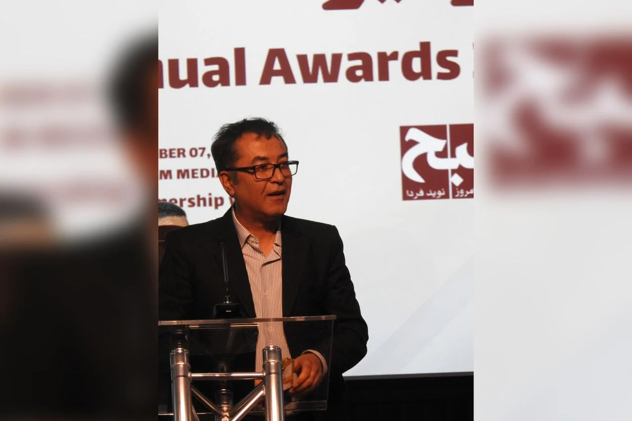 Niamatullah Ebrahimi accepts the Akhgar Enlightenment Statuette at the 8AM Media Awards ceremony, honored for his dedication to research and awareness in Afghanistan. (Photo Credit: 8am.media)