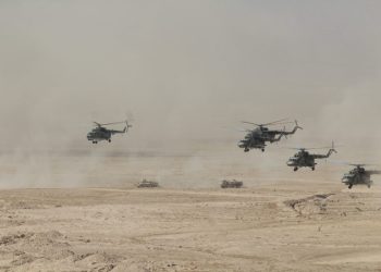 Military helicopters and ground vehicles participate in a joint operation in desert terrain during a Collective Security Treaty Organization exercise. (Photo Credit: CSTO)
