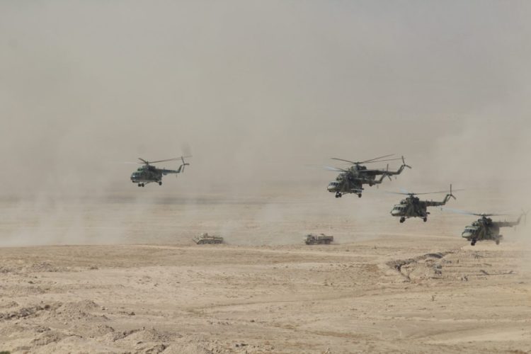 Military helicopters and ground vehicles participate in a joint operation in desert terrain during a Collective Security Treaty Organization exercise. (Photo Credit: CSTO)