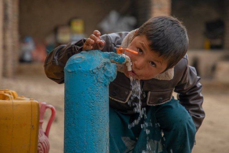 A young child drinks water from a rehabilitated water supply system in Afghanistan, part of UNICEF's program to provide clean drinking water to deprived communities. (Photo Credit: UNICEF)